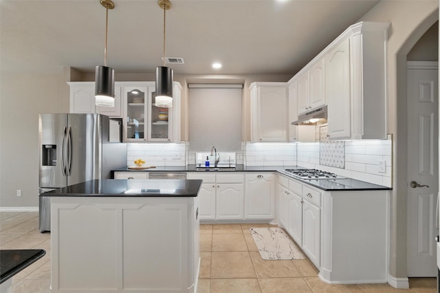 kitchen featuring a sink, dark countertops, arched walkways, and appliances with stainless steel finishes