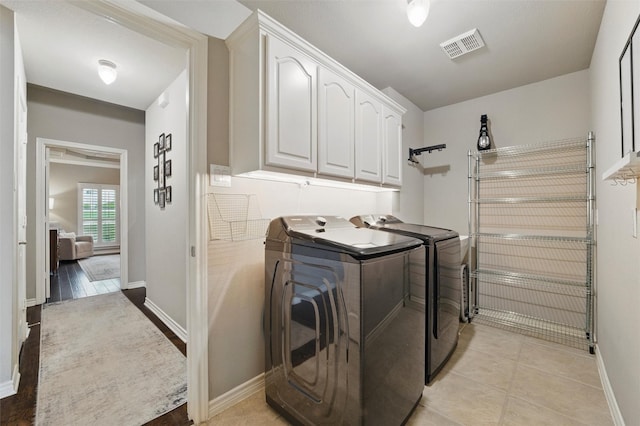 washroom with washing machine and clothes dryer, baseboards, visible vents, and cabinet space