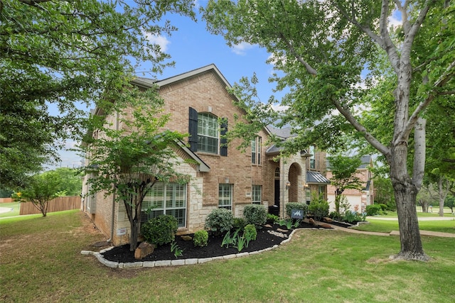 traditional home featuring brick siding, fence, and a front yard