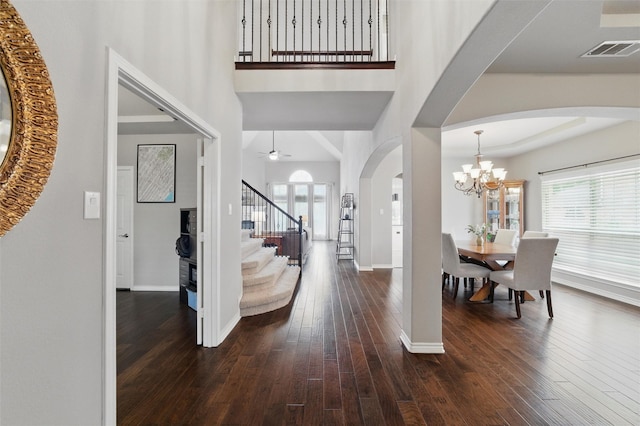foyer with visible vents, arched walkways, hardwood / wood-style flooring, and stairway