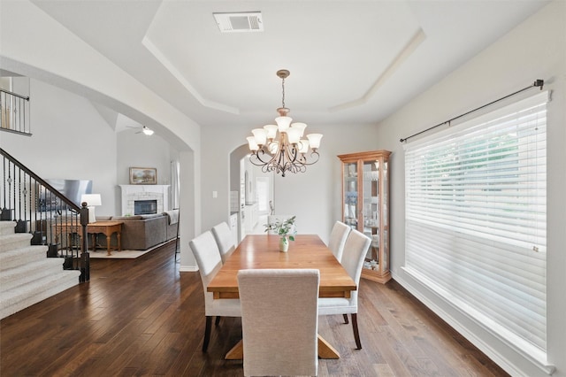 3401 Wentworth Way, Highland Village, TX 75077 - dining room with a glass covered fireplace, stairway, a tray ceiling, ceiling fan, and dark wood finished floors