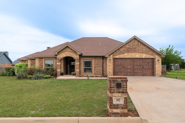 ranch-style home featuring brick siding, a shingled roof, a front yard, and an attached garage