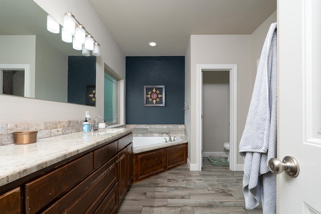 full bathroom with a garden tub, toilet, recessed lighting, wood finished floors, and vanity