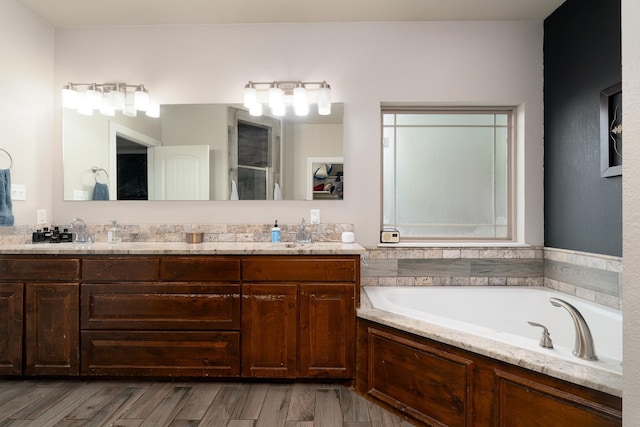full bathroom with a shower stall, a sink, double vanity, a bath, and wood finished floors