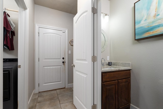 bathroom featuring tile patterned flooring, baseboards, vanity, and washer / clothes dryer