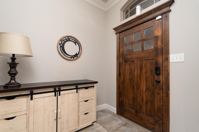 foyer with light tile patterned floors, ornamental molding, and baseboards