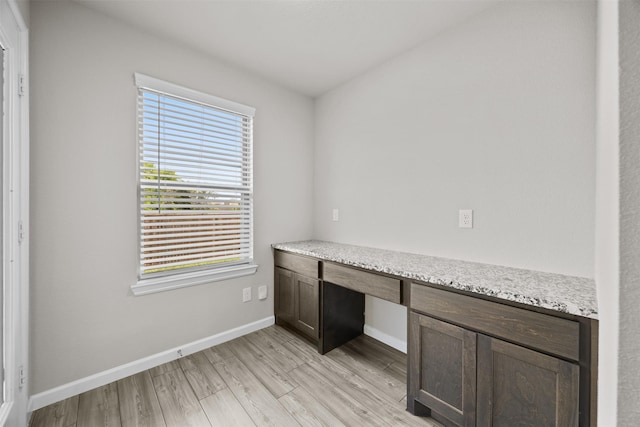 unfurnished office with baseboards, built in study area, and light wood finished floors
