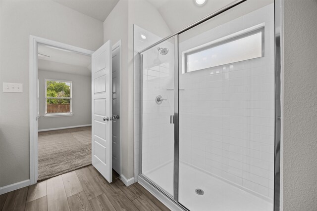 full bathroom featuring wood finished floors, a shower stall, and baseboards