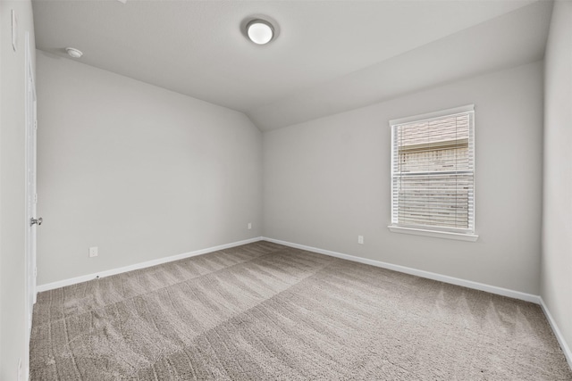 empty room with carpet flooring, vaulted ceiling, and baseboards
