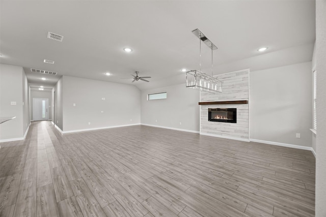 unfurnished living room featuring light wood-type flooring, visible vents, ceiling fan, and a fireplace