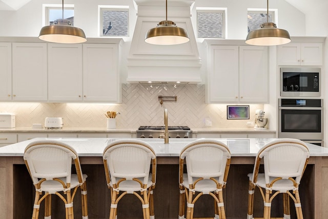kitchen with built in microwave, tasteful backsplash, a center island with sink, and stainless steel oven
