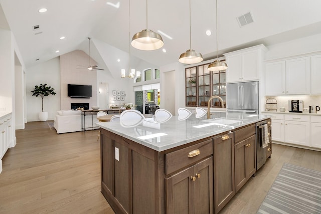 kitchen featuring a sink, appliances with stainless steel finishes, a large fireplace, ceiling fan, and high vaulted ceiling