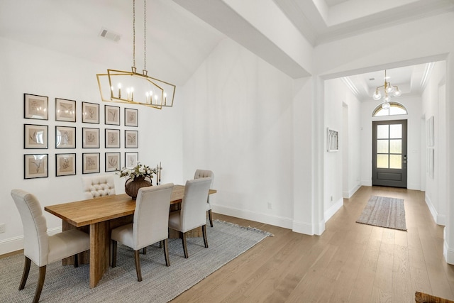 dining space featuring wood finished floors, a chandelier, crown molding, and visible vents