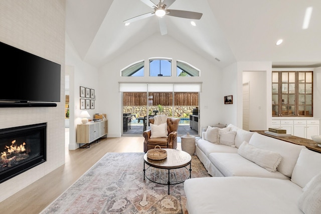 living room with light wood-style floors, recessed lighting, a fireplace, a ceiling fan, and high vaulted ceiling