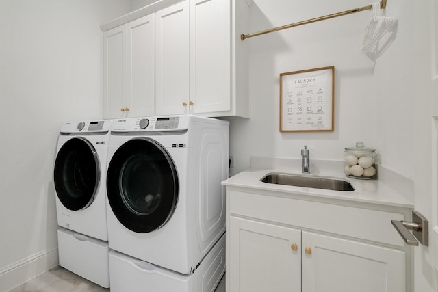 clothes washing area with a sink, baseboards, cabinet space, and washing machine and dryer