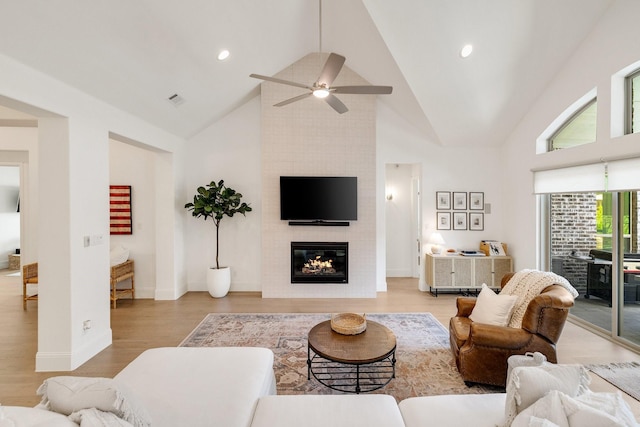 living area with visible vents, a fireplace, wood finished floors, a ceiling fan, and high vaulted ceiling