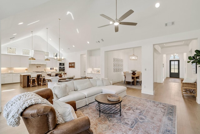 living room with visible vents, light wood-style floors, recessed lighting, high vaulted ceiling, and ceiling fan with notable chandelier