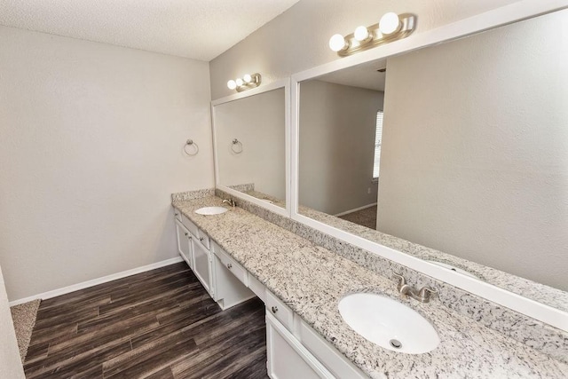 4109 Orchard Hill Dr, Arlington, TX 76016 - bathroom featuring baseboards, wood finished floors, double vanity, and a sink