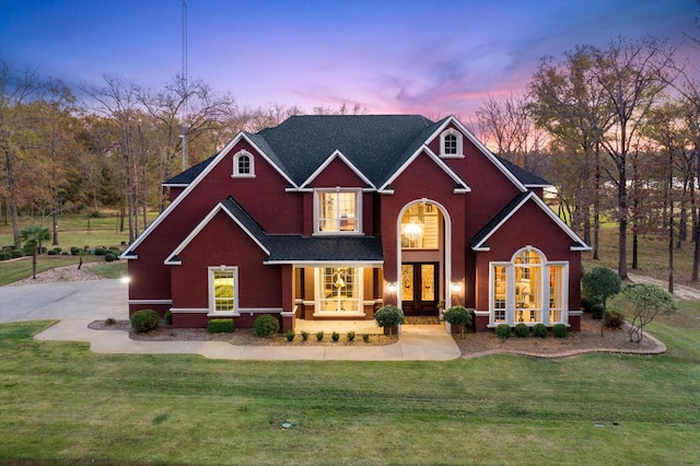 view of front of property with covered porch, french doors, and a front lawn