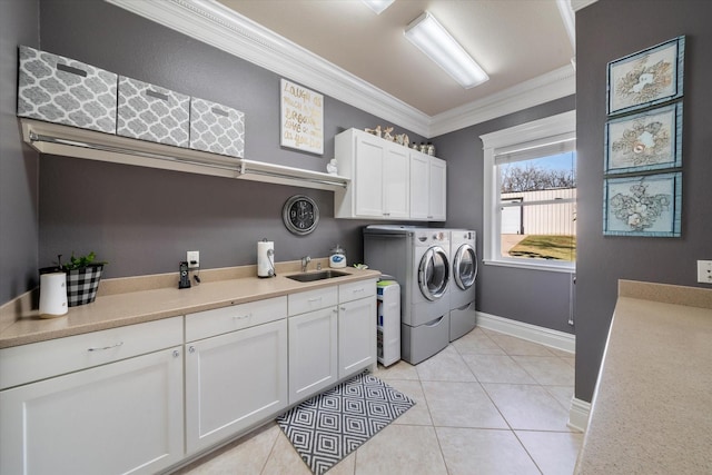 clothes washing area featuring cabinet space, ornamental molding, a sink, baseboards, and washing machine and dryer