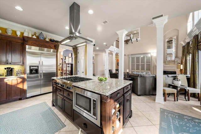 kitchen with decorative backsplash, built in appliances, decorative columns, visible vents, and island range hood
