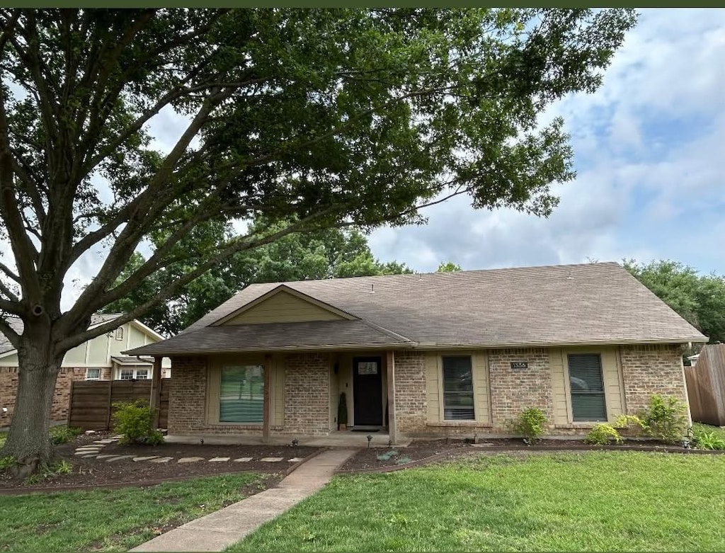 ranch-style house with fence, brick siding, and a front yard