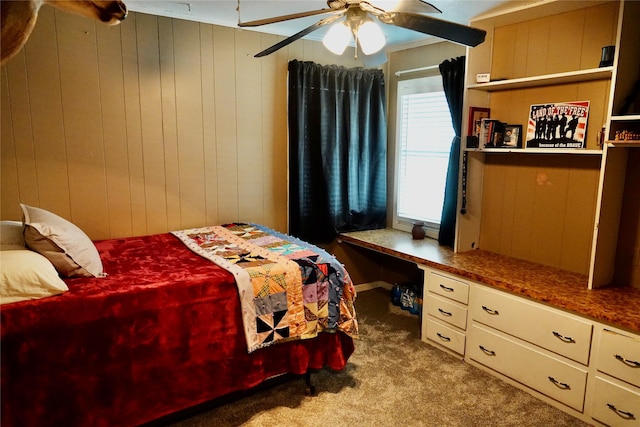 bedroom with wooden walls, a ceiling fan, built in desk, and carpet floors