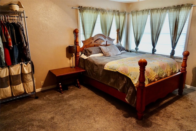 carpeted bedroom with baseboards, multiple windows, and a textured wall