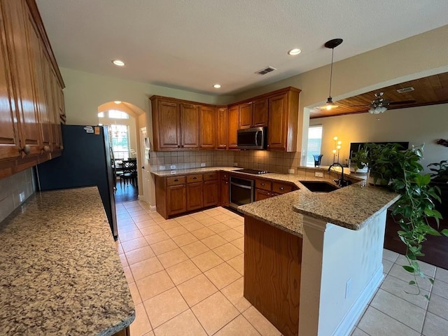 104 Misty Glen Ln, Murphy, TX 75094 - kitchen featuring brown cabinets, a sink, stainless steel appliances, arched walkways, and a peninsula