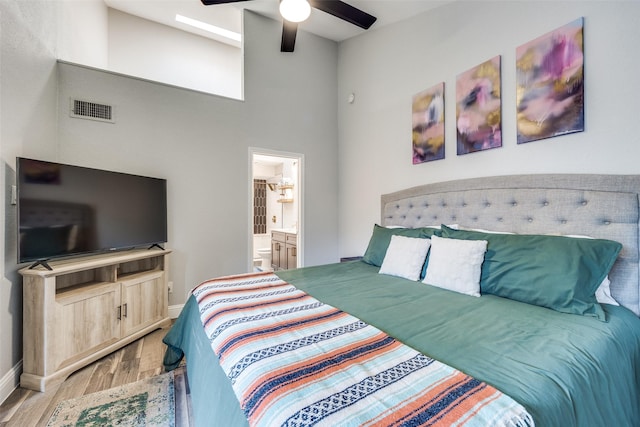 bedroom with visible vents, ceiling fan, baseboards, wood finished floors, and ensuite bath