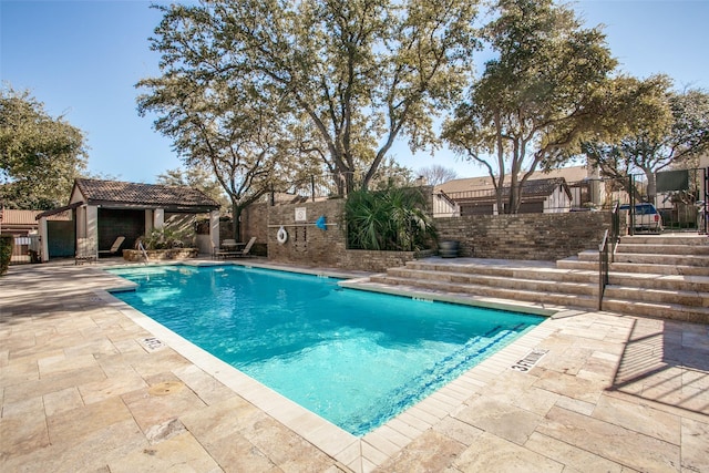 community pool featuring a patio area, fence private yard, and an outbuilding