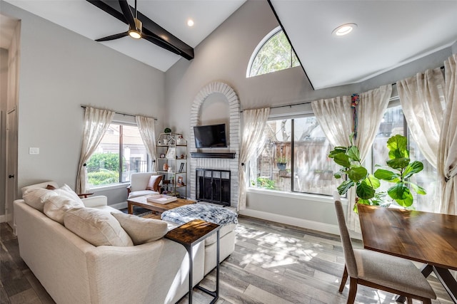 living area with a brick fireplace, a wealth of natural light, wood finished floors, and baseboards