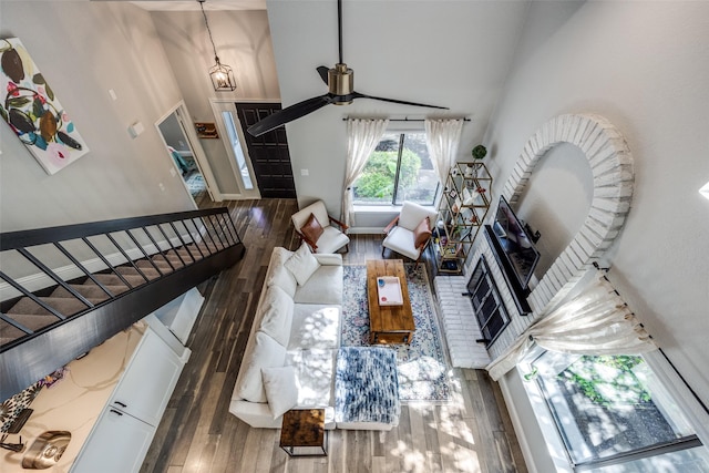 living area with stairway, wood finished floors, a ceiling fan, and high vaulted ceiling