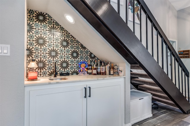 bar with a sink, stairway, vaulted ceiling, wood finished floors, and wet bar