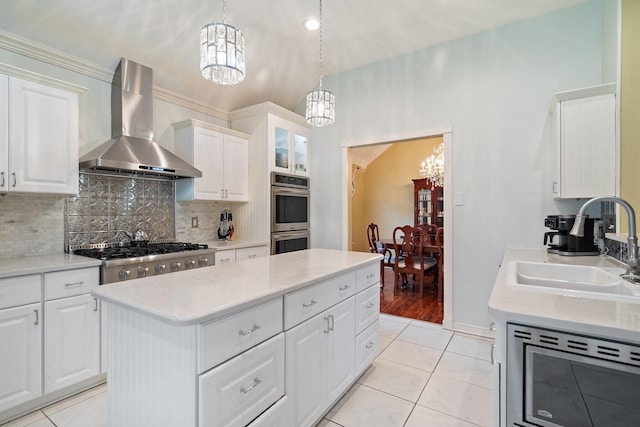 kitchen featuring wall chimney exhaust hood, an inviting chandelier, appliances with stainless steel finishes, and light countertops