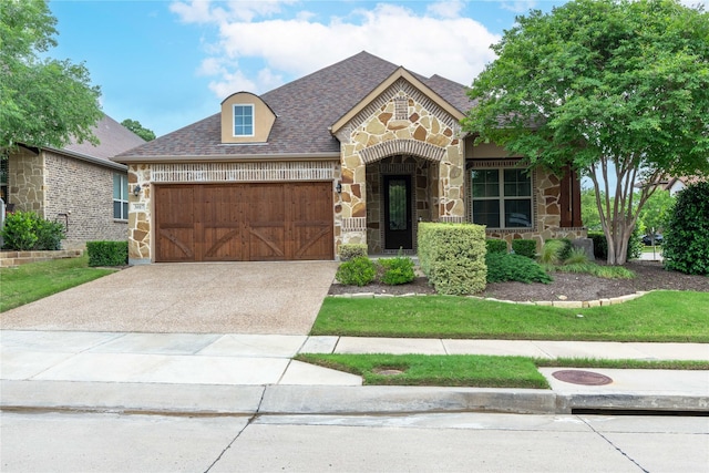 3017 Bella Lago Dr, Denton, TX 76210 - french country home featuring a garage, roof with shingles, stone siding, and concrete driveway