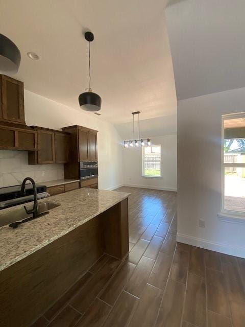 1716 Oldham Ln, Abilene, TX 79602 - kitchen featuring light stone countertops, a wealth of natural light, hanging light fixtures, and a sink