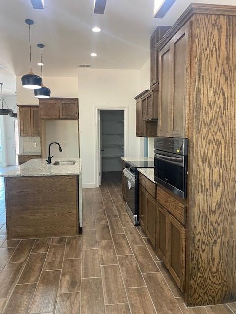 1716 Oldham Ln, Abilene, TX 79602 - kitchen with a sink, wood tiled floor, oven, light stone countertops, and hanging light fixtures