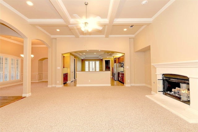 unfurnished living room with a multi sided fireplace, ceiling fan, ornamental molding, and light colored carpet
