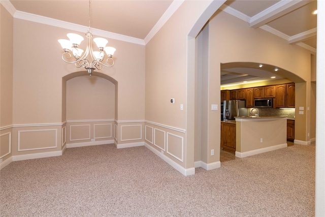 spare room with crown molding, arched walkways, light colored carpet, and a notable chandelier