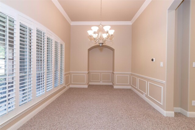empty room with carpet floors, wainscoting, a chandelier, and ornamental molding
