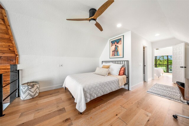bedroom with a fireplace, ceiling fan, lofted ceiling, baseboards, and wood finished floors