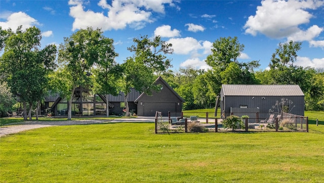rear view of property featuring a garage, an outbuilding, a yard, a pole building, and fence