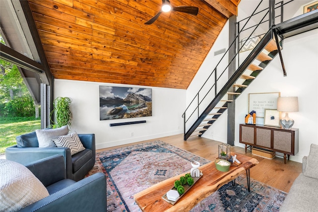 living area featuring lofted ceiling, stairway, visible vents, and a ceiling fan