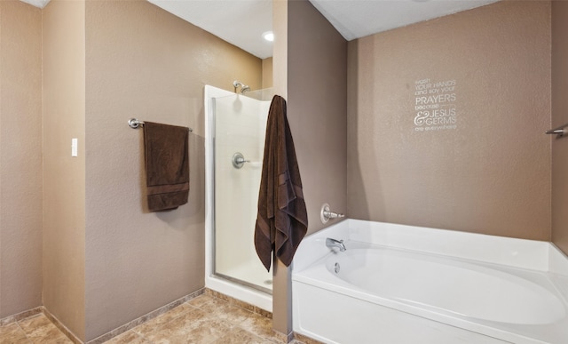 bathroom featuring baseboards, a bath, and a shower stall