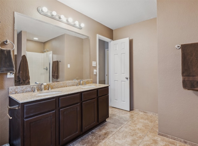 full bath with a sink, tile patterned flooring, double vanity, and a shower