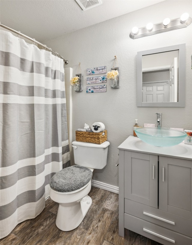 bathroom featuring visible vents, vanity, wood finished floors, toilet, and baseboards