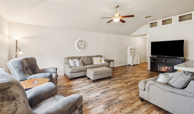 living room featuring a ceiling fan, baseboards, vaulted ceiling, and wood finished floors