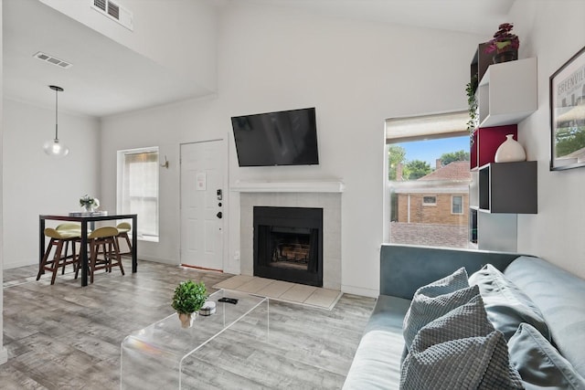 living room featuring wood finished floors, visible vents, a tiled fireplace, and baseboards