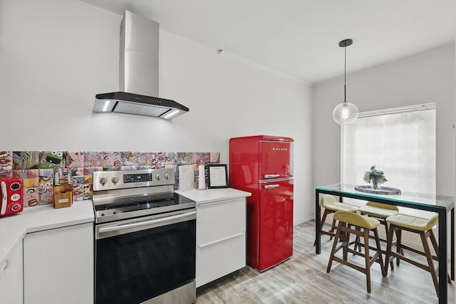 kitchen featuring stainless steel range with electric stovetop, light wood-style flooring, wall chimney range hood, and light countertops